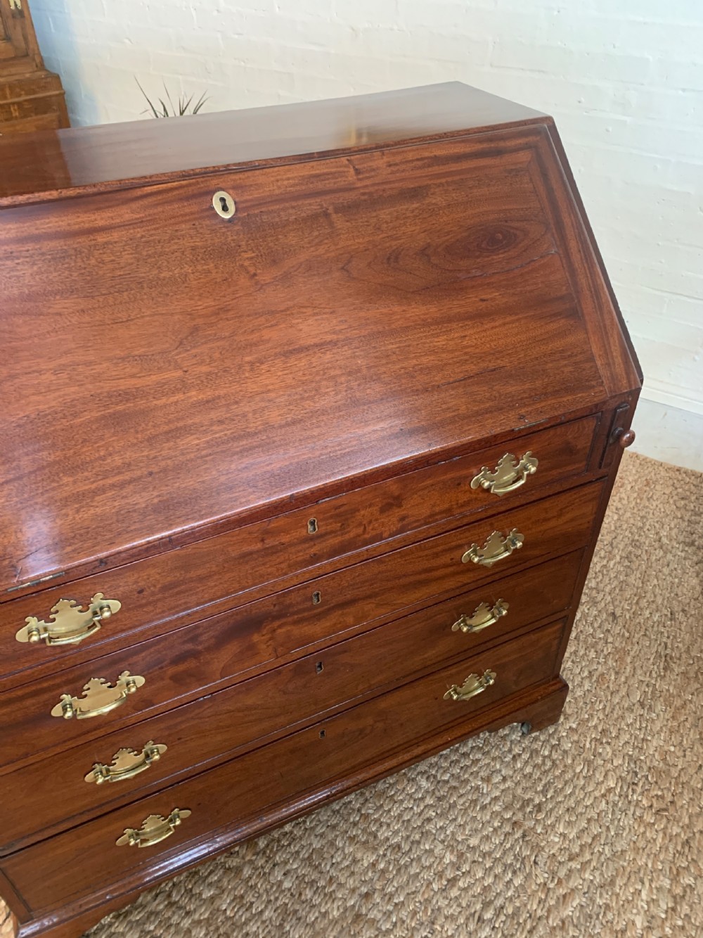 A Georgian mahogany slant-front writing bureau featuring four graduated drawers with brass batwing handles and bracket feet. View XVIII