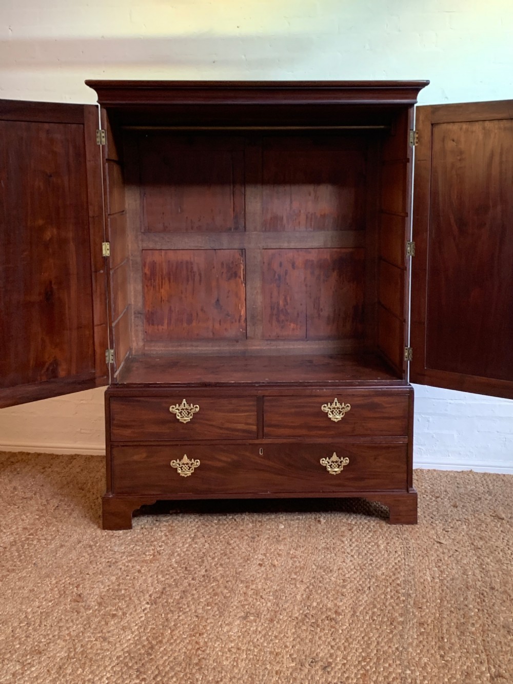 A 19th-century mahogany linen press featuring a two-door upper cupboard above a base with drawers and brass handles. View II