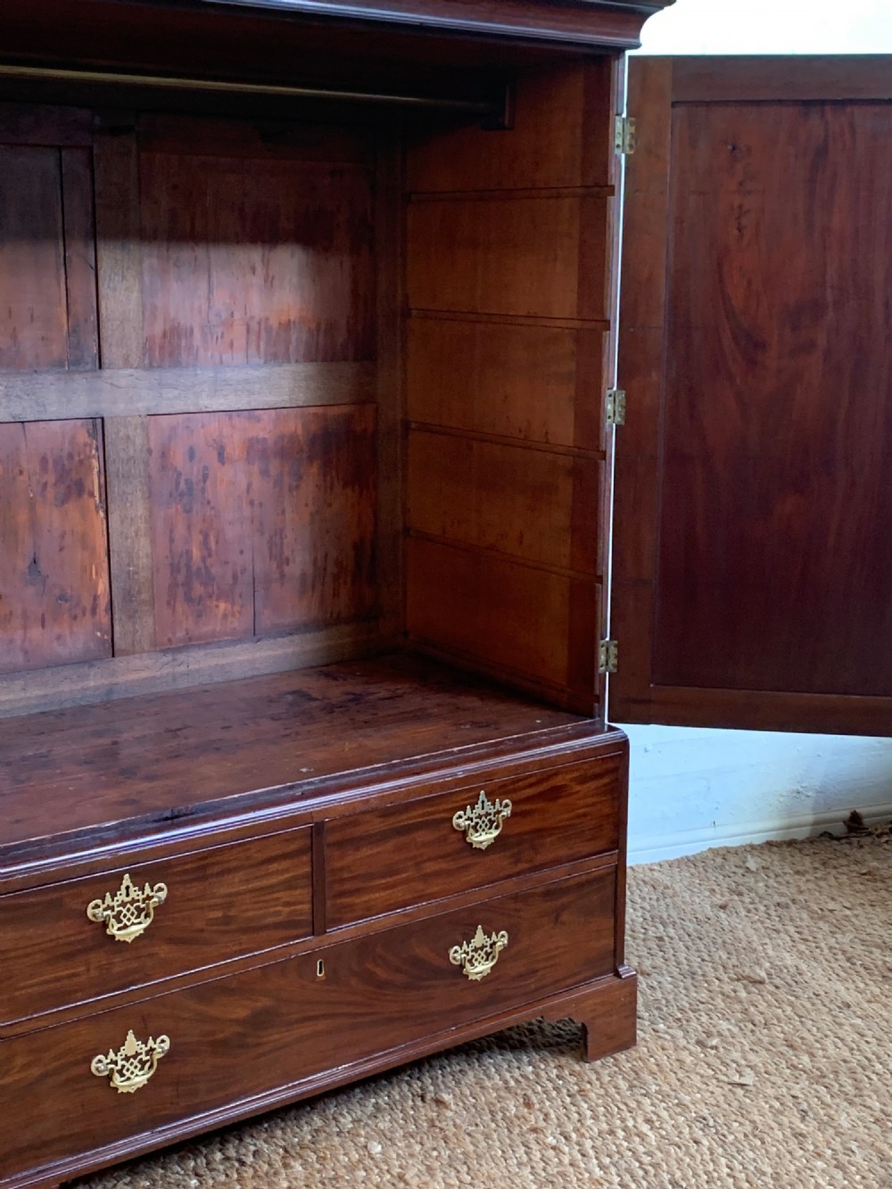 A 19th-century mahogany linen press featuring a two-door upper cupboard above a base with drawers and brass handles. View III