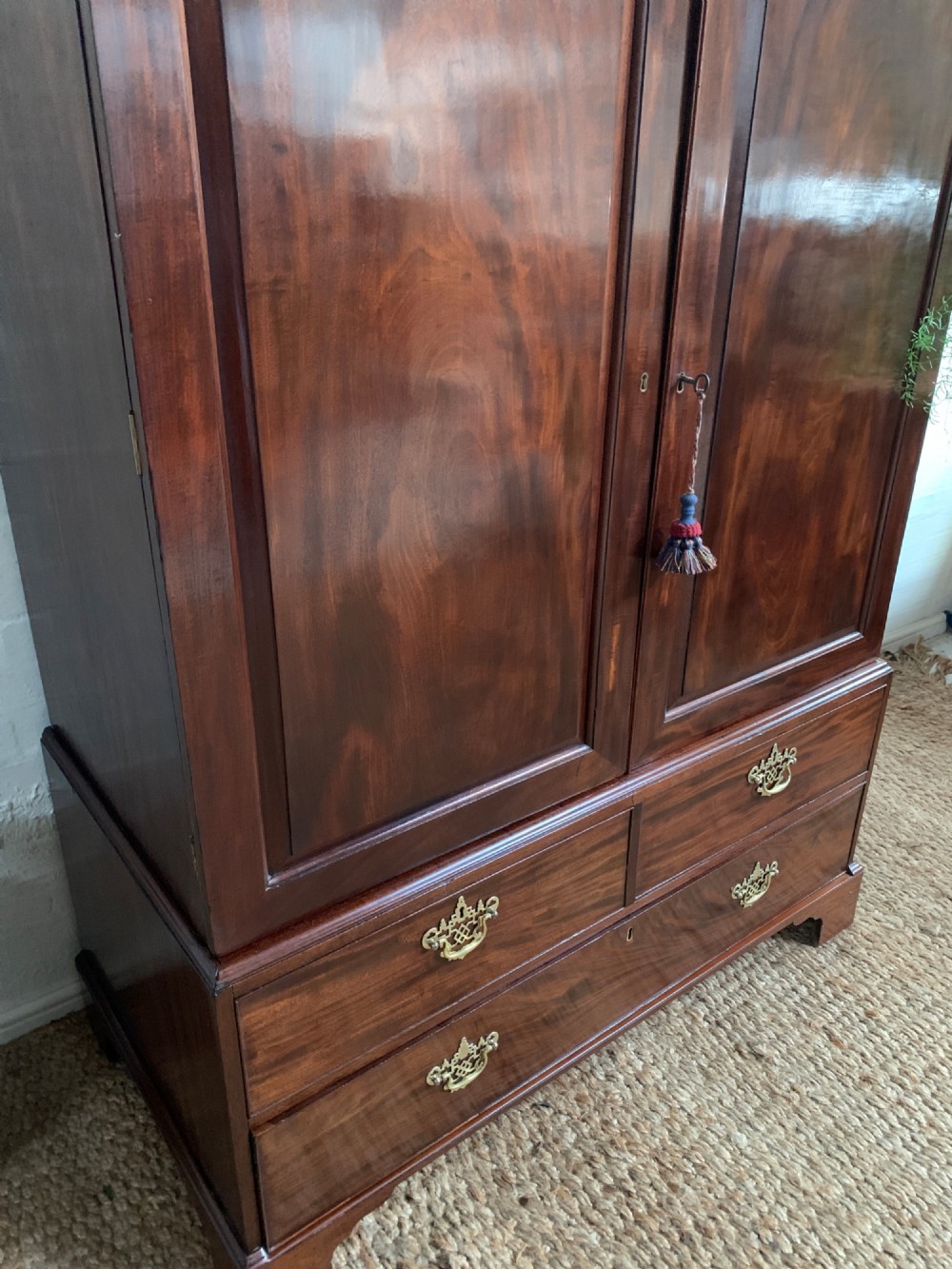 A 19th-century mahogany linen press featuring a two-door upper cupboard above a base with drawers and brass handles. View VII