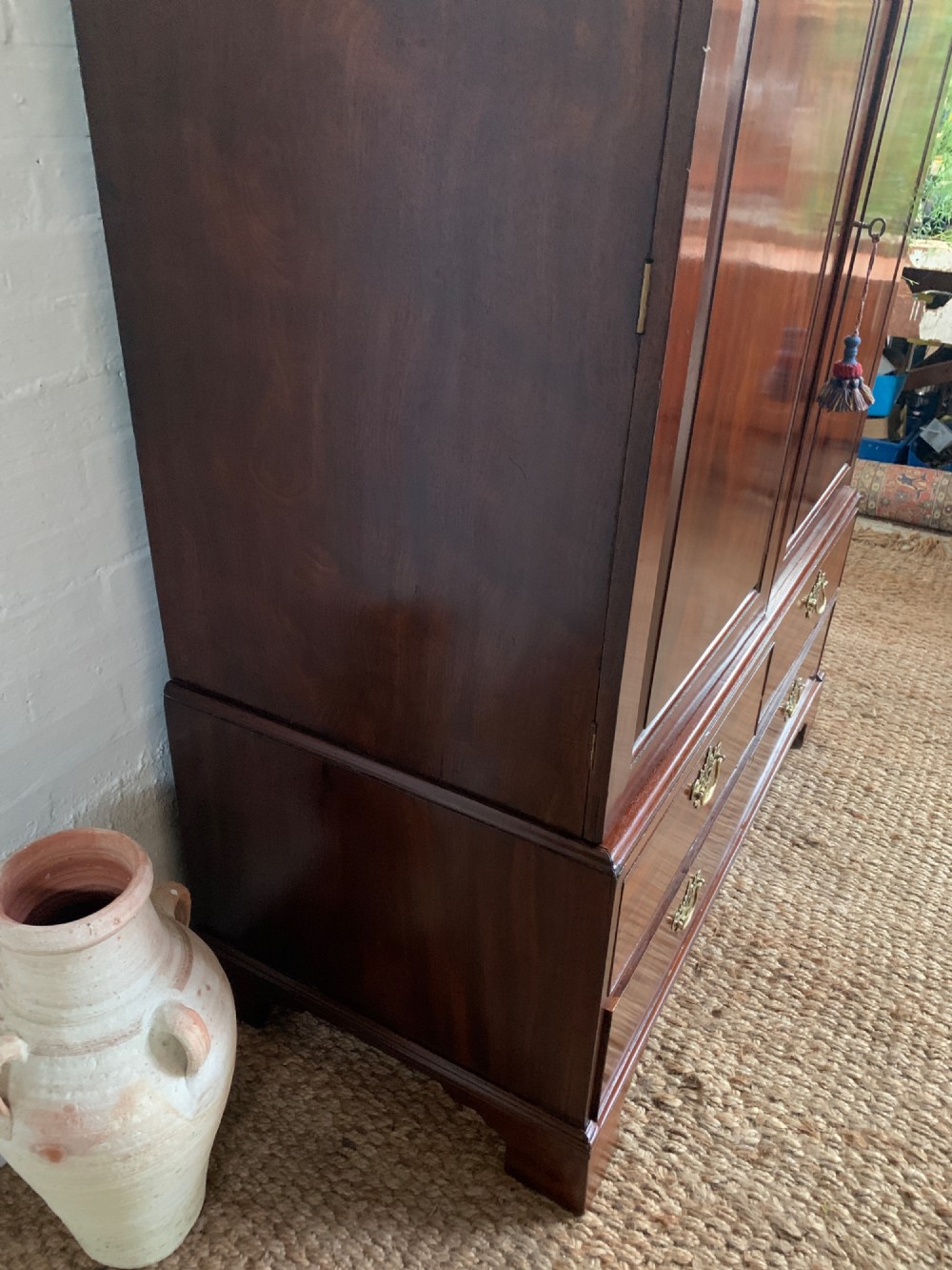 A 19th-century mahogany linen press featuring a two-door upper cupboard above a base with drawers and brass handles. View VIII