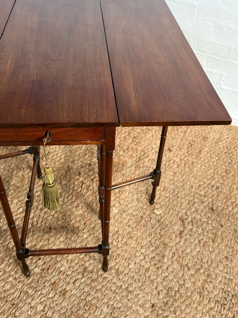 An Edwardian solid dark mahogany drop-leaf side table featuring turned faux-bamboo legs, a central drawer with a key, and a double-tier stretcher base. View V