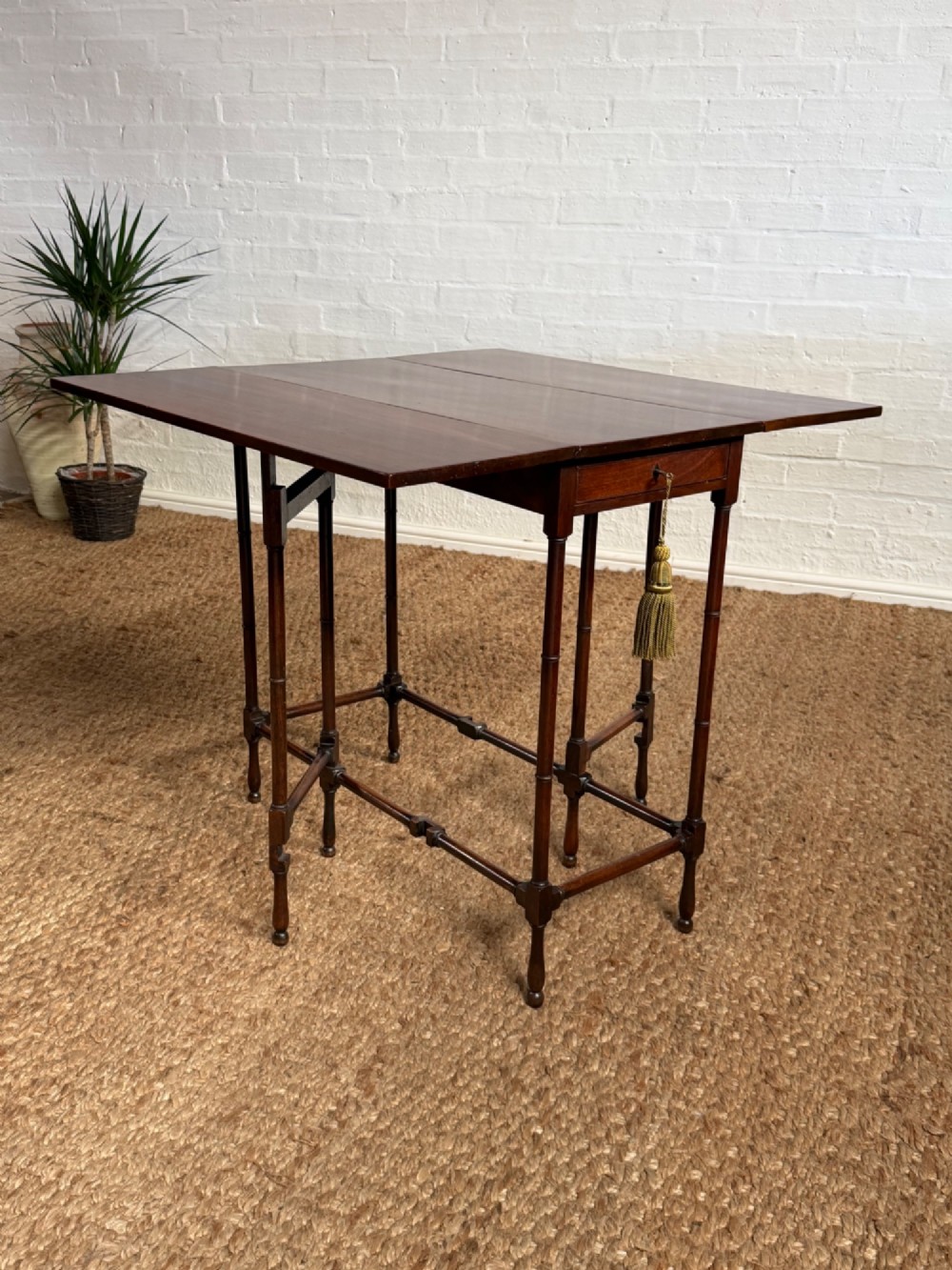 An Edwardian solid dark mahogany drop-leaf side table featuring turned faux-bamboo legs, a central drawer with a key, and a double-tier stretcher base. View VI