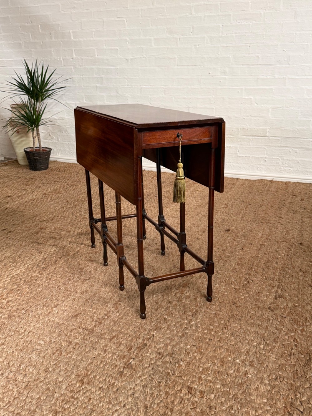 An Edwardian solid dark mahogany drop-leaf side table featuring turned faux-bamboo legs, a central drawer with a key, and a double-tier stretcher base. View VII