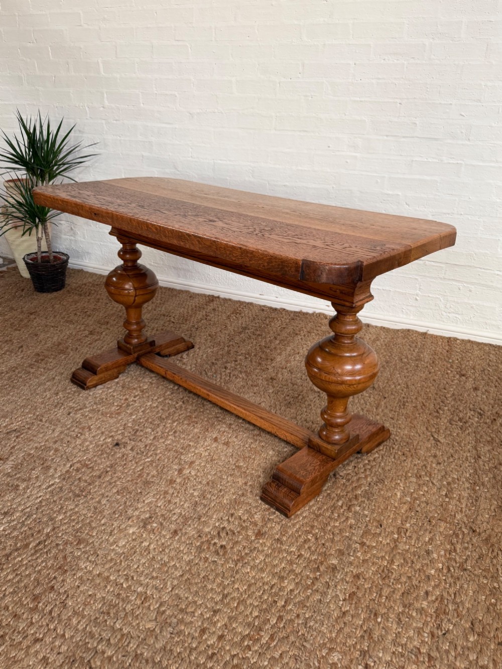 A small solid oak refectory style dining table featuring bulbous turned baluster legs and a floor-level central stretcher.