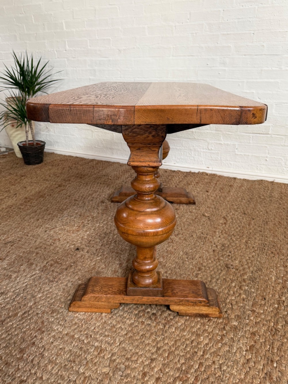 A small solid oak refectory style dining table featuring bulbous turned baluster legs and a floor-level central stretcher. View VII
