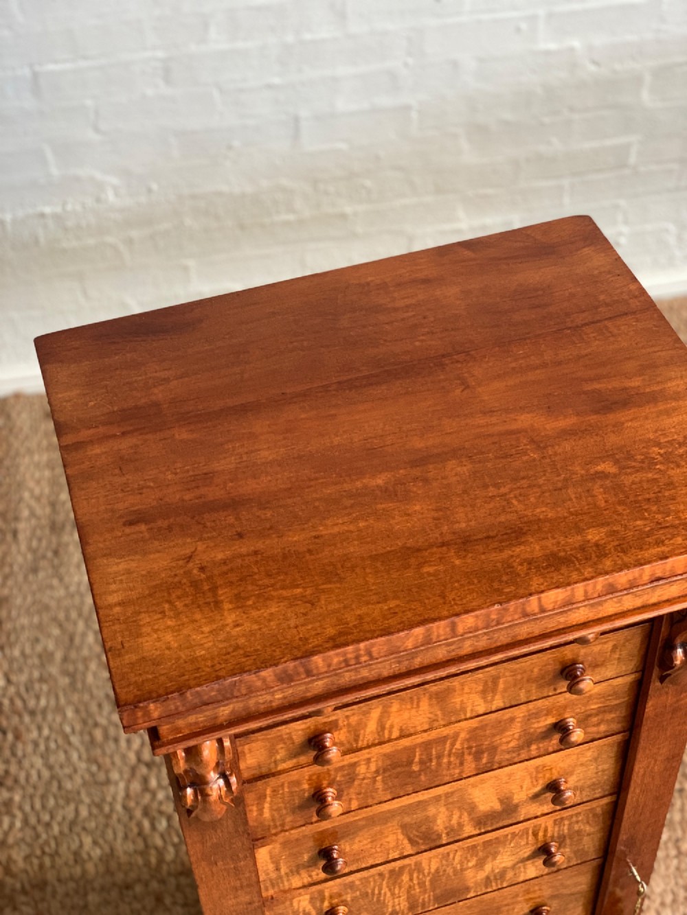 A tall Victorian figured mahogany Wellington chest with eight graduated drawers, turned wooden knobs, carved corbels, and a hinged side locking bar. View VII