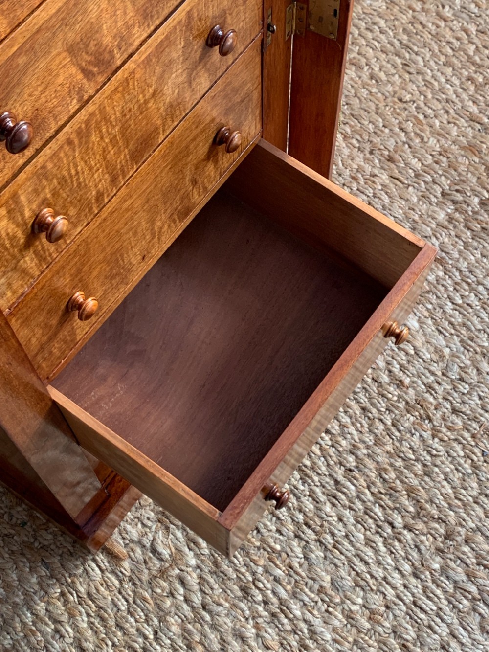 A tall Victorian figured mahogany Wellington chest with eight graduated drawers, turned wooden knobs, carved corbels, and a hinged side locking bar. View IX