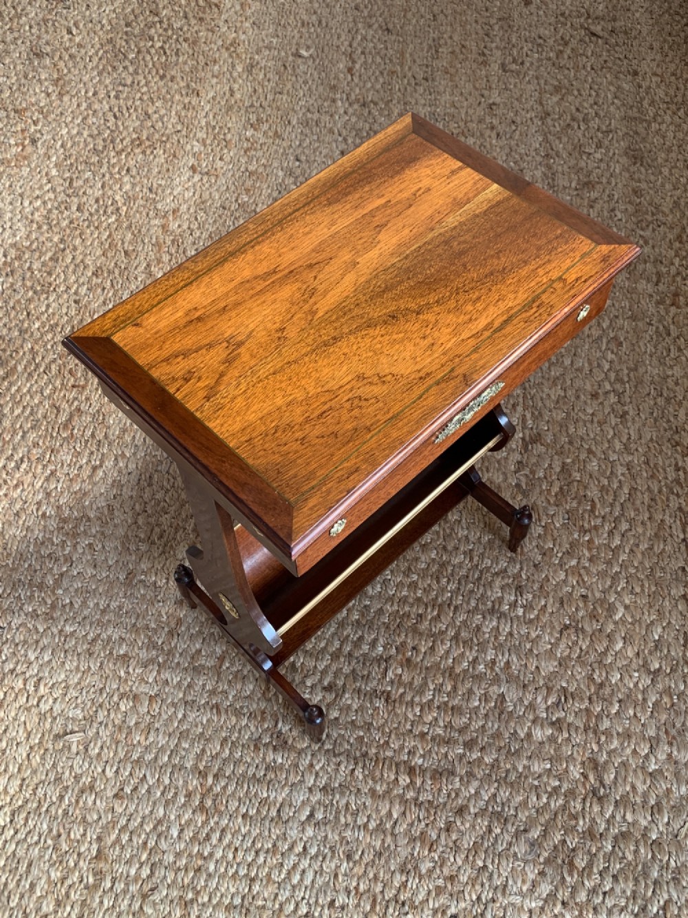 A dark mahogany Canterbury side table featuring a rectangular top, a single shallow drawer with brass knobs, and a lower V-shaped magazine trough supported on shaped uprights. View II