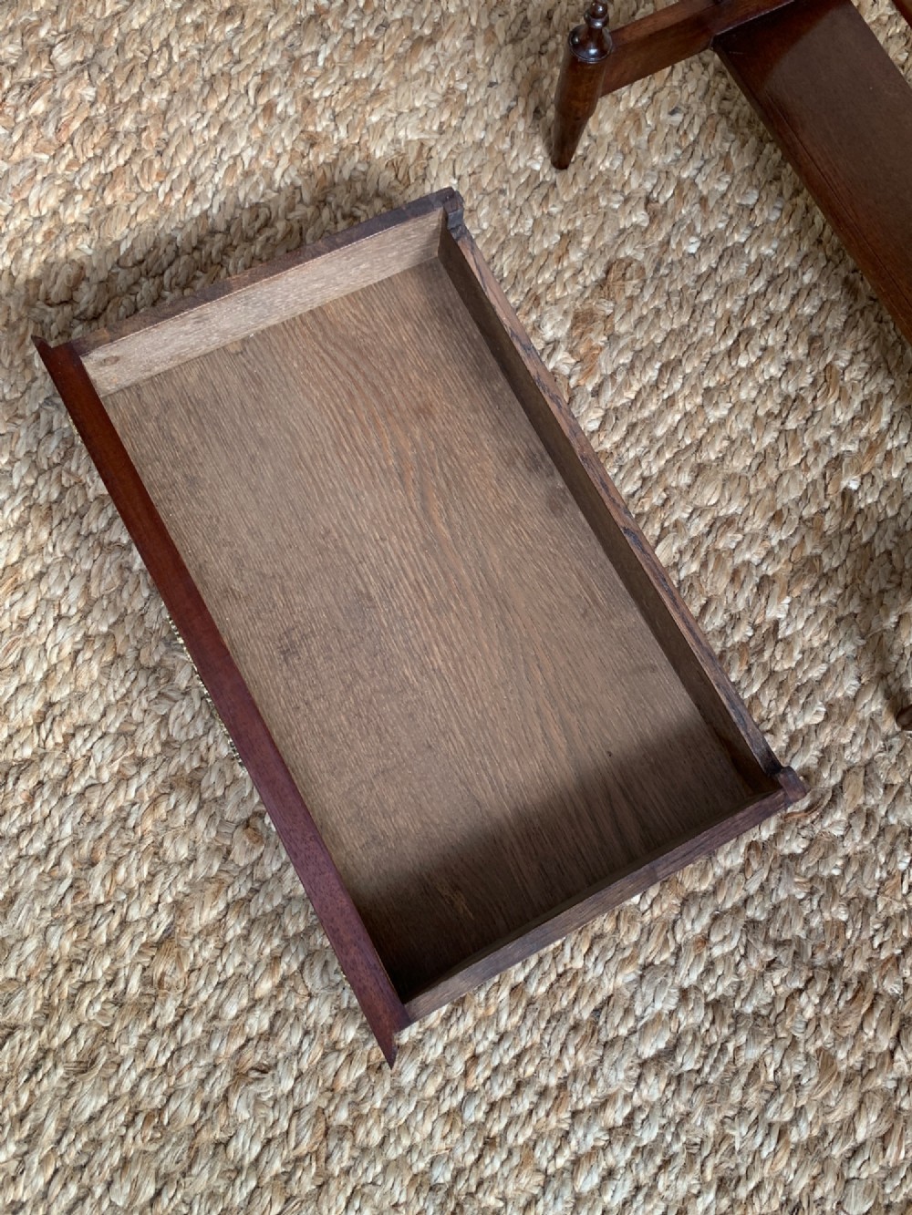 A dark mahogany Canterbury side table featuring a rectangular top, a single shallow drawer with brass knobs, and a lower V-shaped magazine trough supported on shaped uprights. View V