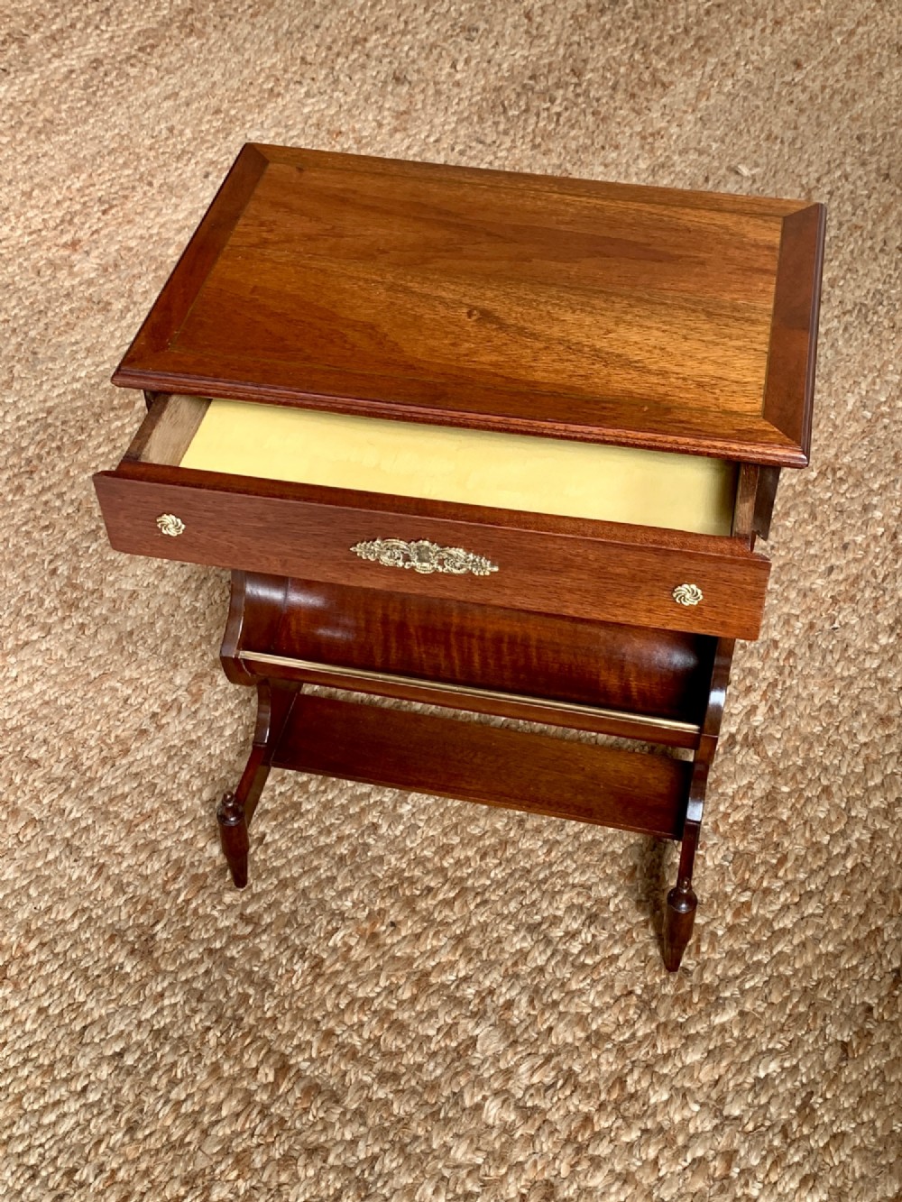 A dark mahogany Canterbury side table featuring a rectangular top, a single shallow drawer with brass knobs, and a lower V-shaped magazine trough supported on shaped uprights. View VII