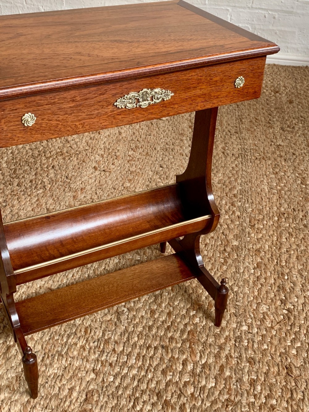 A dark mahogany Canterbury side table featuring a rectangular top, a single shallow drawer with brass knobs, and a lower V-shaped magazine trough supported on shaped uprights. View VIII