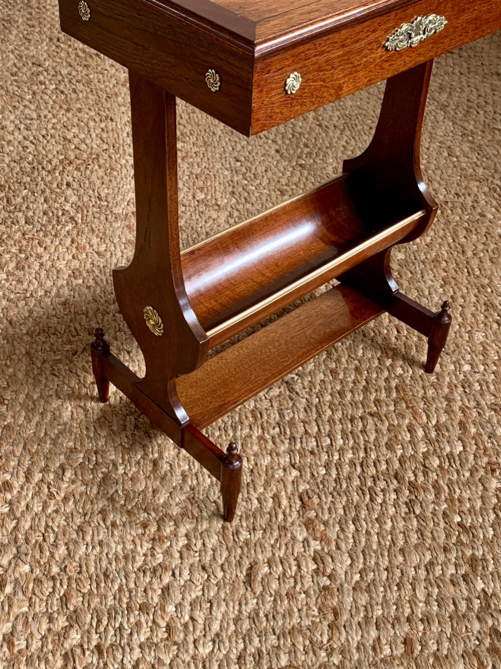 A dark mahogany Canterbury side table featuring a rectangular top, a single shallow drawer with brass knobs, and a lower V-shaped magazine trough supported on shaped uprights. View IX