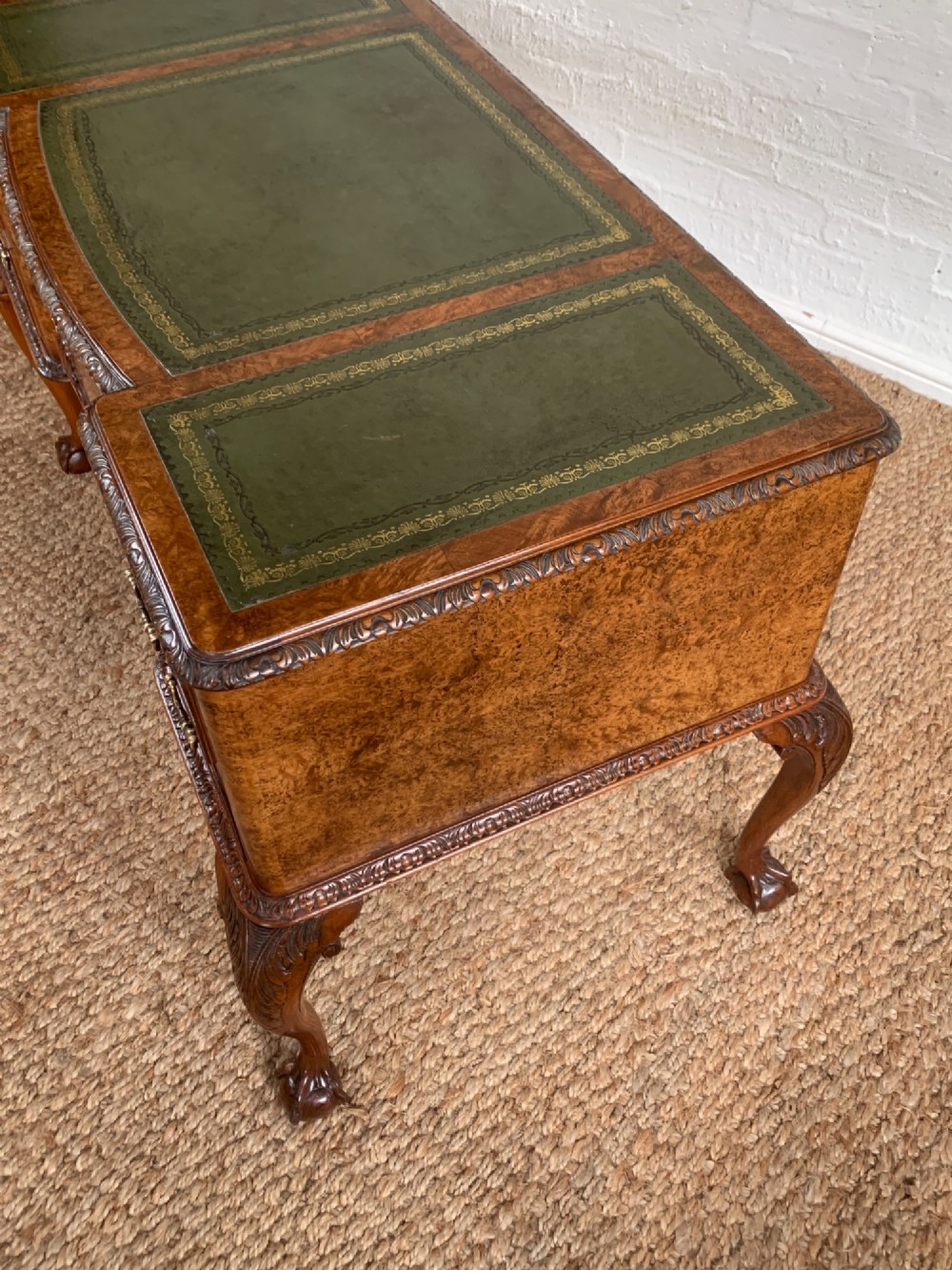 A burr walnut kneehole writing desk with four drawers, carved cabriole legs with claw and ball feet, and a green leather writing surface. View IV