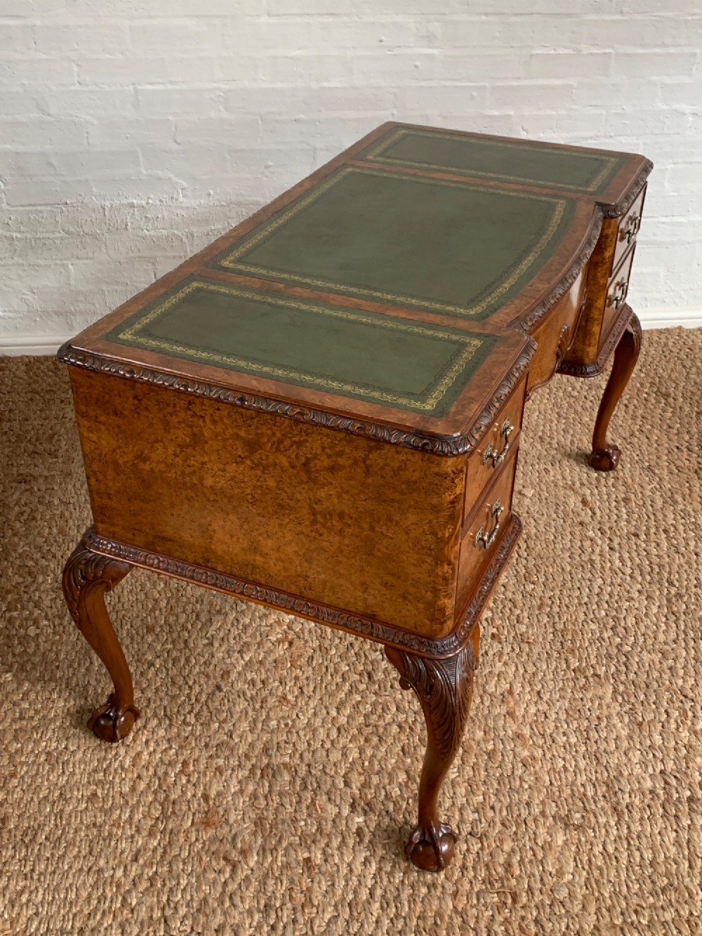 A burr walnut kneehole writing desk with four drawers, carved cabriole legs with claw and ball feet, and a green leather writing surface. View VII