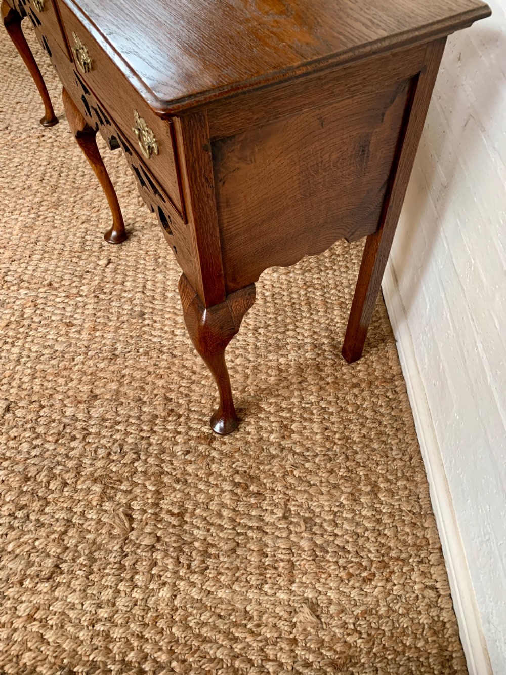 An Edwardian oak dresser base featuring three drawers with brass handles, a decorative pierced fretwork apron, and four cabriole legs terminating in pad feet. View IV