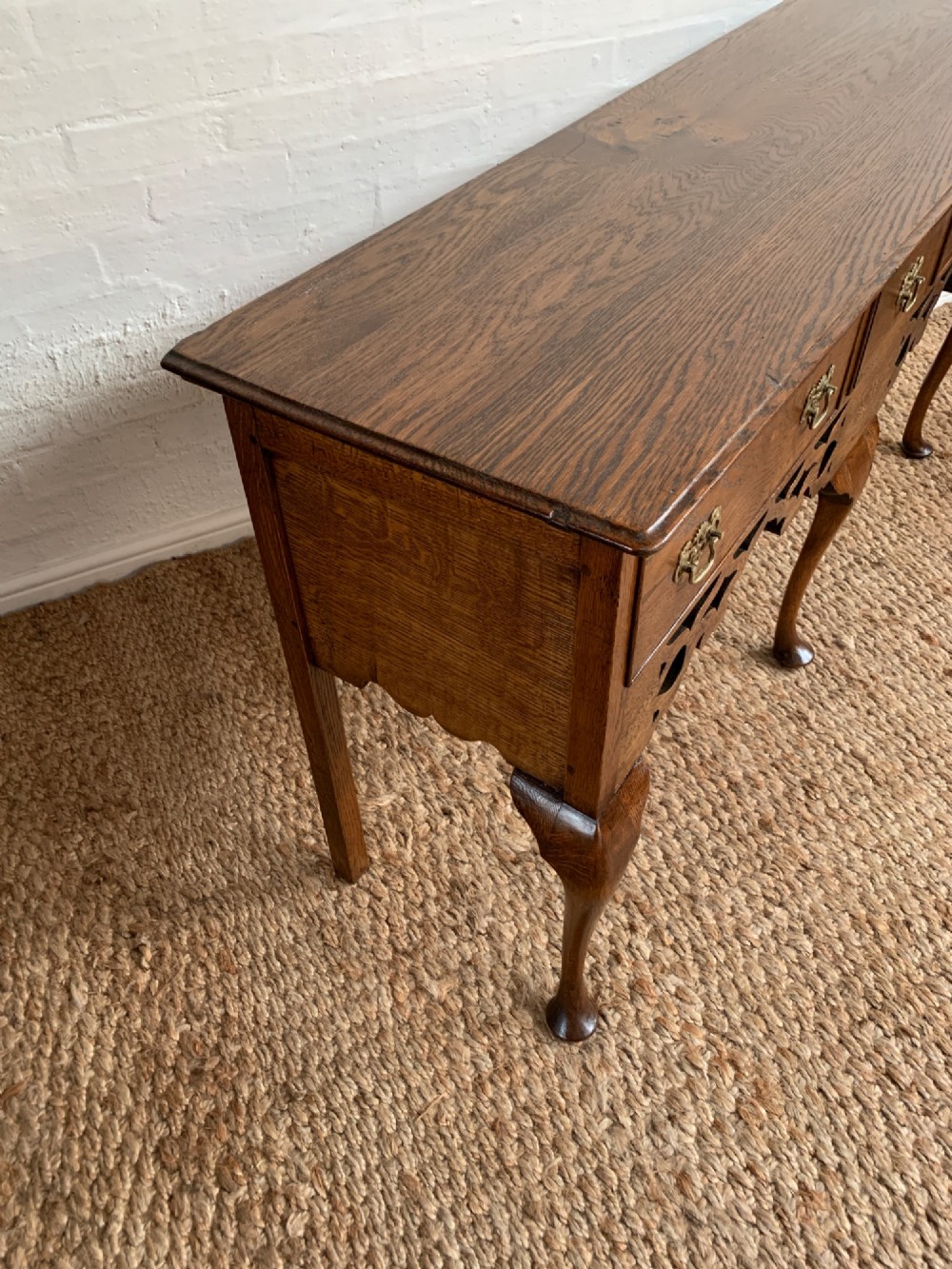 An Edwardian oak dresser base featuring three drawers with brass handles, a decorative pierced fretwork apron, and four cabriole legs terminating in pad feet. View V