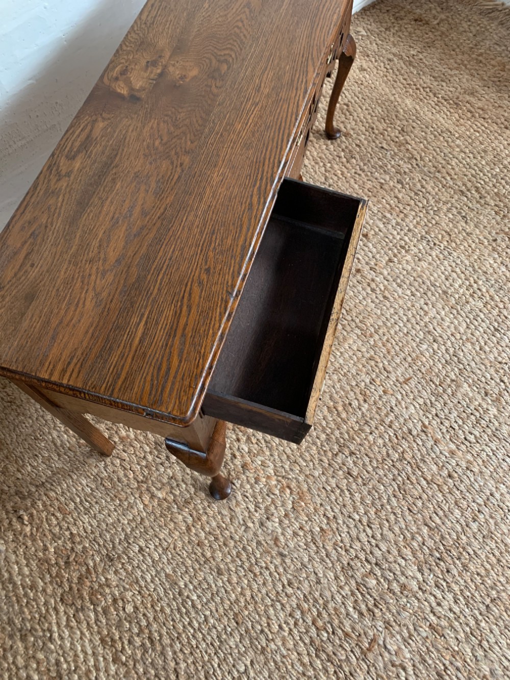An Edwardian oak dresser base featuring three drawers with brass handles, a decorative pierced fretwork apron, and four cabriole legs terminating in pad feet. View VII