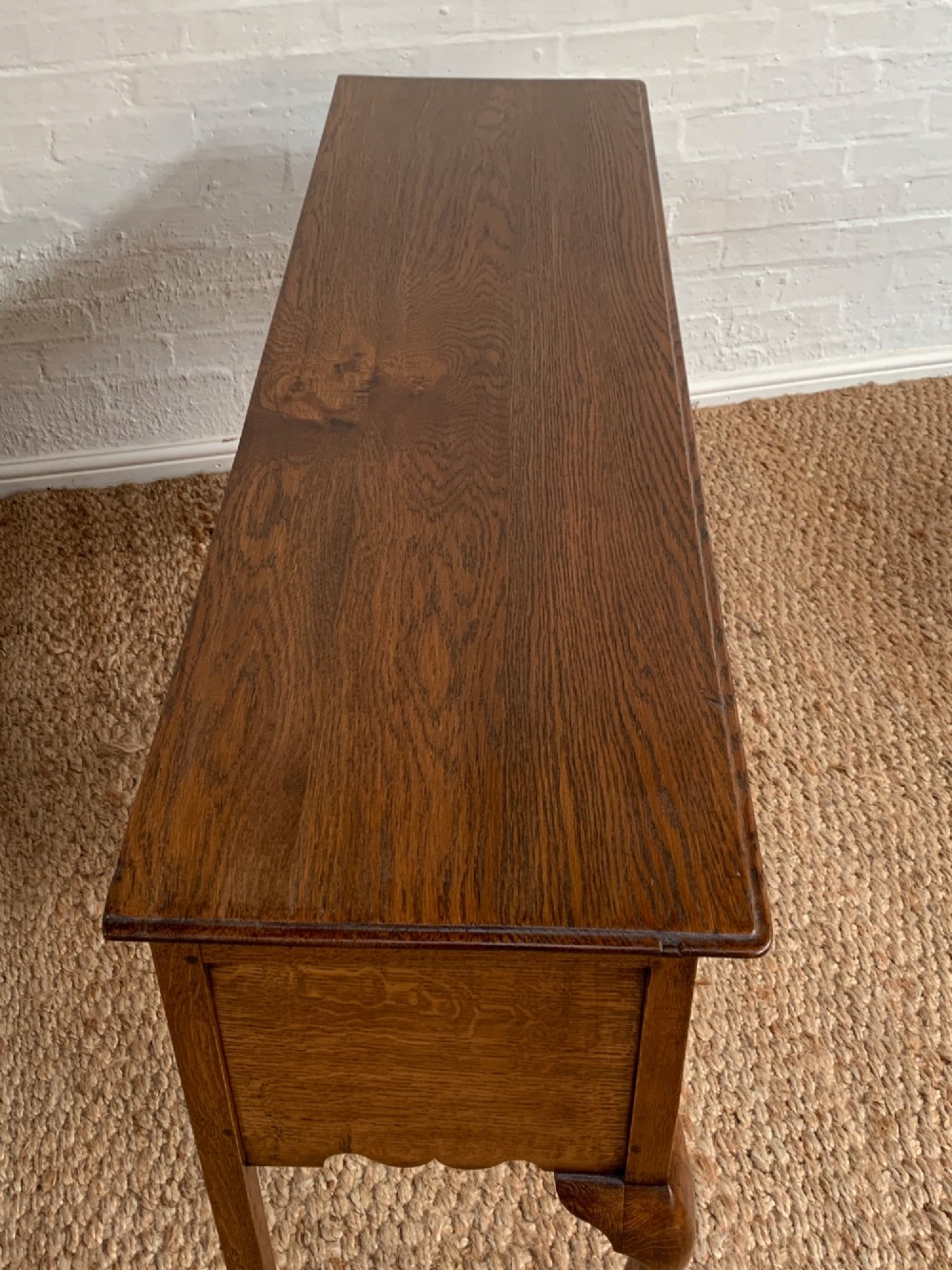 An Edwardian oak dresser base featuring three drawers with brass handles, a decorative pierced fretwork apron, and four cabriole legs terminating in pad feet. View X