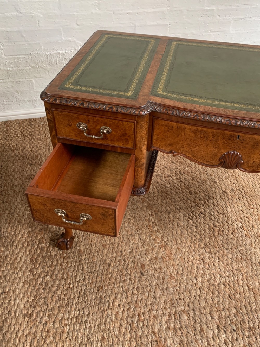 A burr walnut kneehole writing desk with four drawers, carved cabriole legs with claw and ball feet, and a green leather writing surface. View IX
