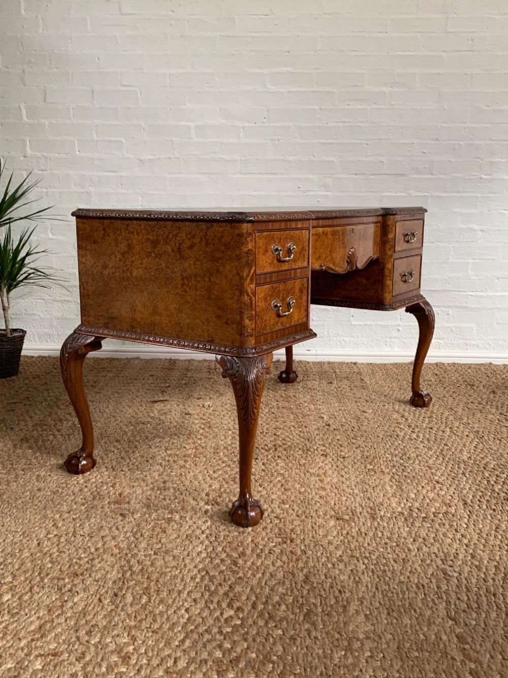 A burr walnut kneehole writing desk with four drawers, carved cabriole legs with claw and ball feet, and a green leather writing surface. View X