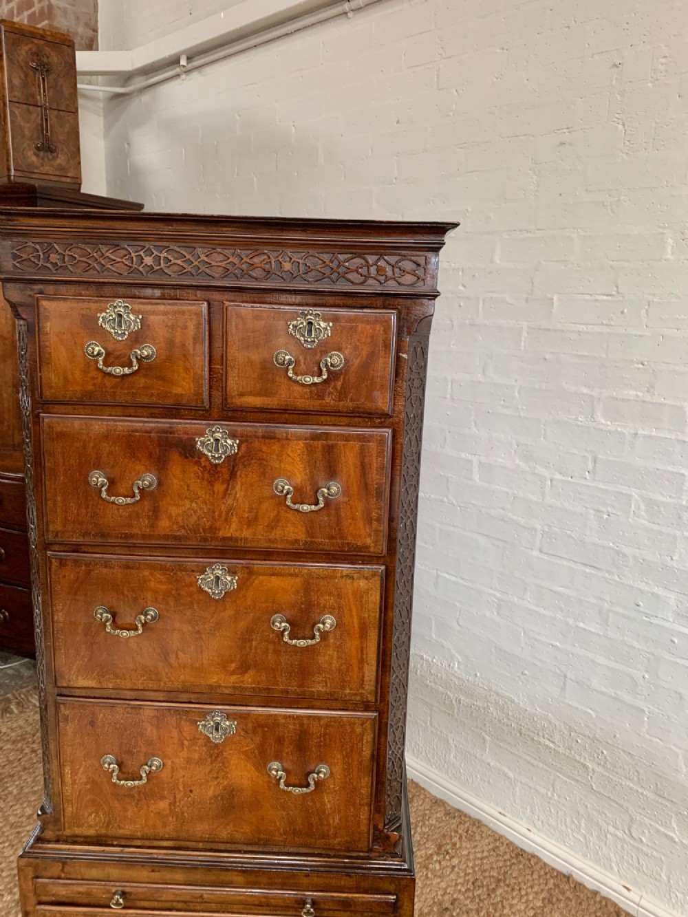 A tall 19th-century George III style burr walnut chest of drawers featuring decorative brass handles, keyhole escutcheons, carved side friezes, and bracket feet. View VIII