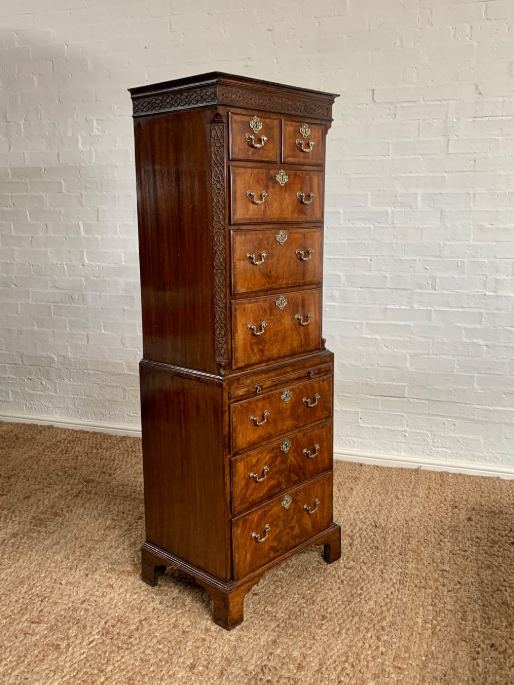 A tall 19th-century George III style burr walnut chest of drawers featuring decorative brass handles, keyhole escutcheons, carved side friezes, and bracket feet. View IX