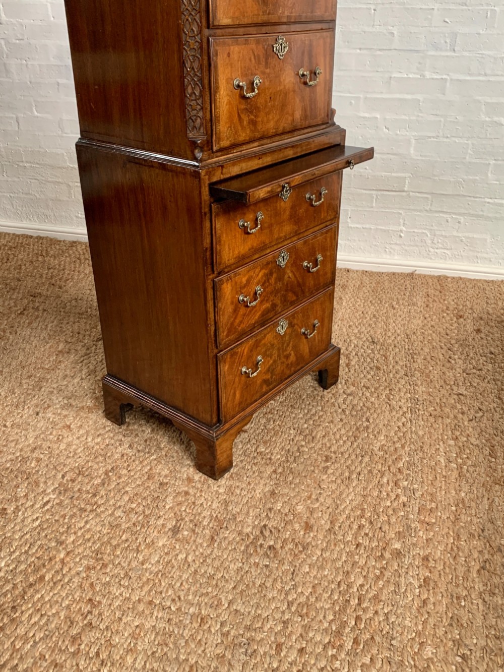 A tall 19th-century George III style burr walnut chest of drawers featuring decorative brass handles, keyhole escutcheons, carved side friezes, and bracket feet. View X