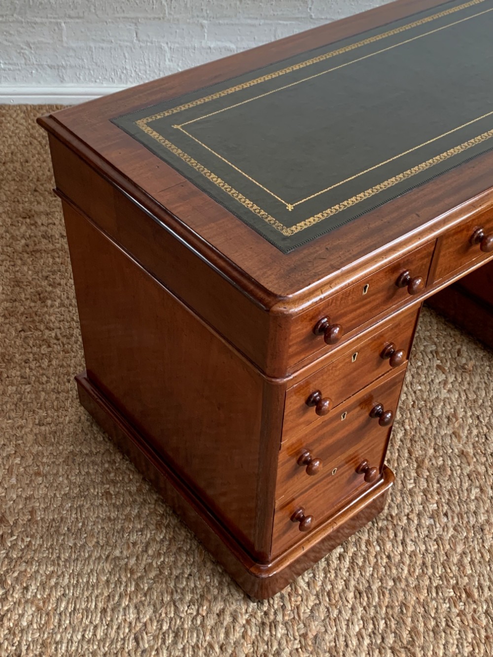 Victorian mahogany pedestal desk featuring an olive green gold-tooled leather inset top and nine drawers with turned wooden knobs. View II