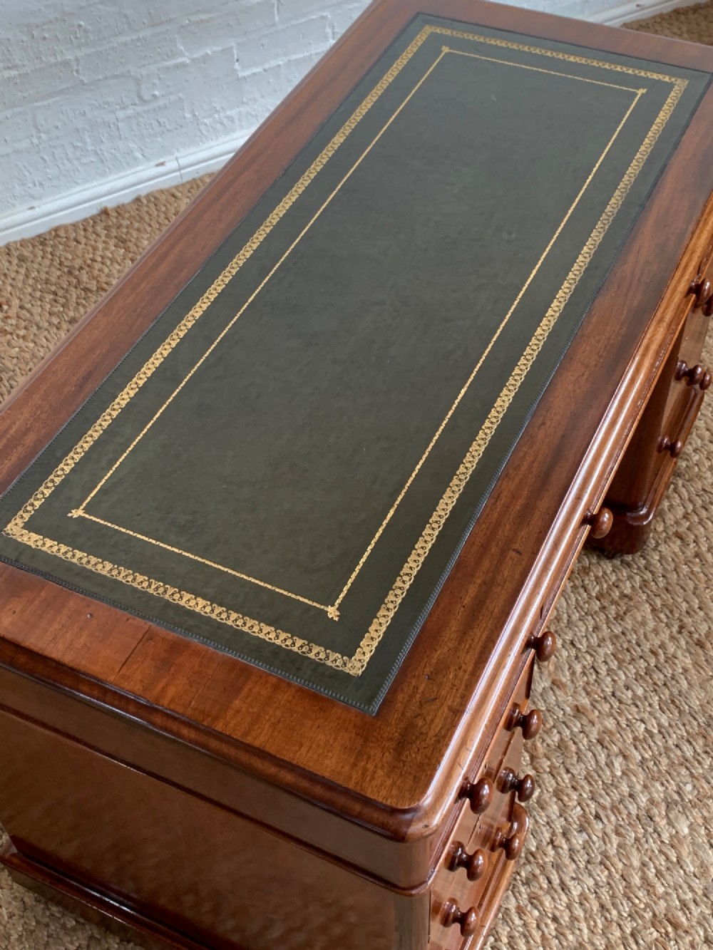 Victorian mahogany pedestal desk featuring an olive green gold-tooled leather inset top and nine drawers with turned wooden knobs. View III