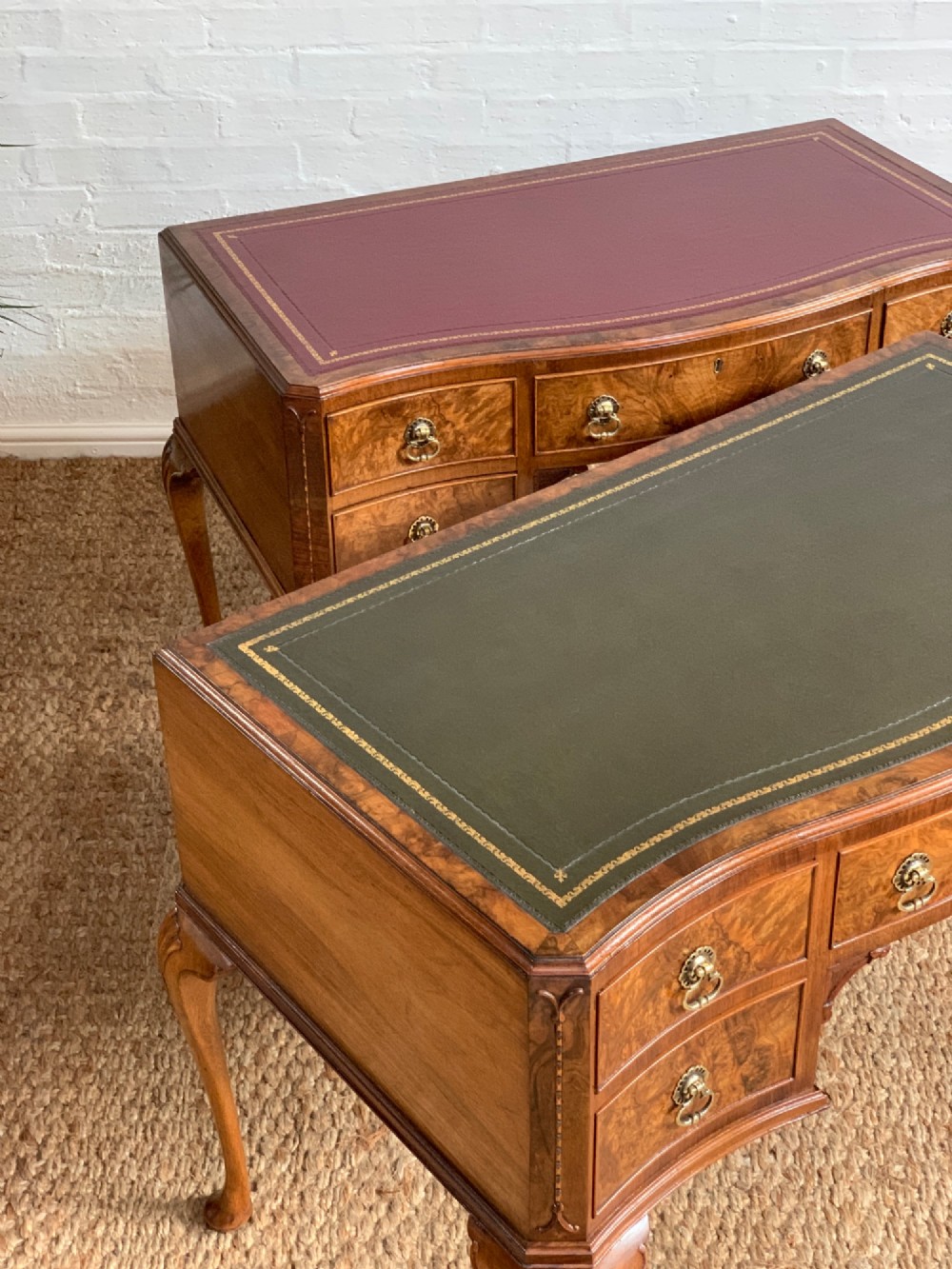 An early 20th-century burr walnut writing desk featuring an inset leather top, kneehole drawer arrangement, brass drop handles, and cabriole legs. View VI