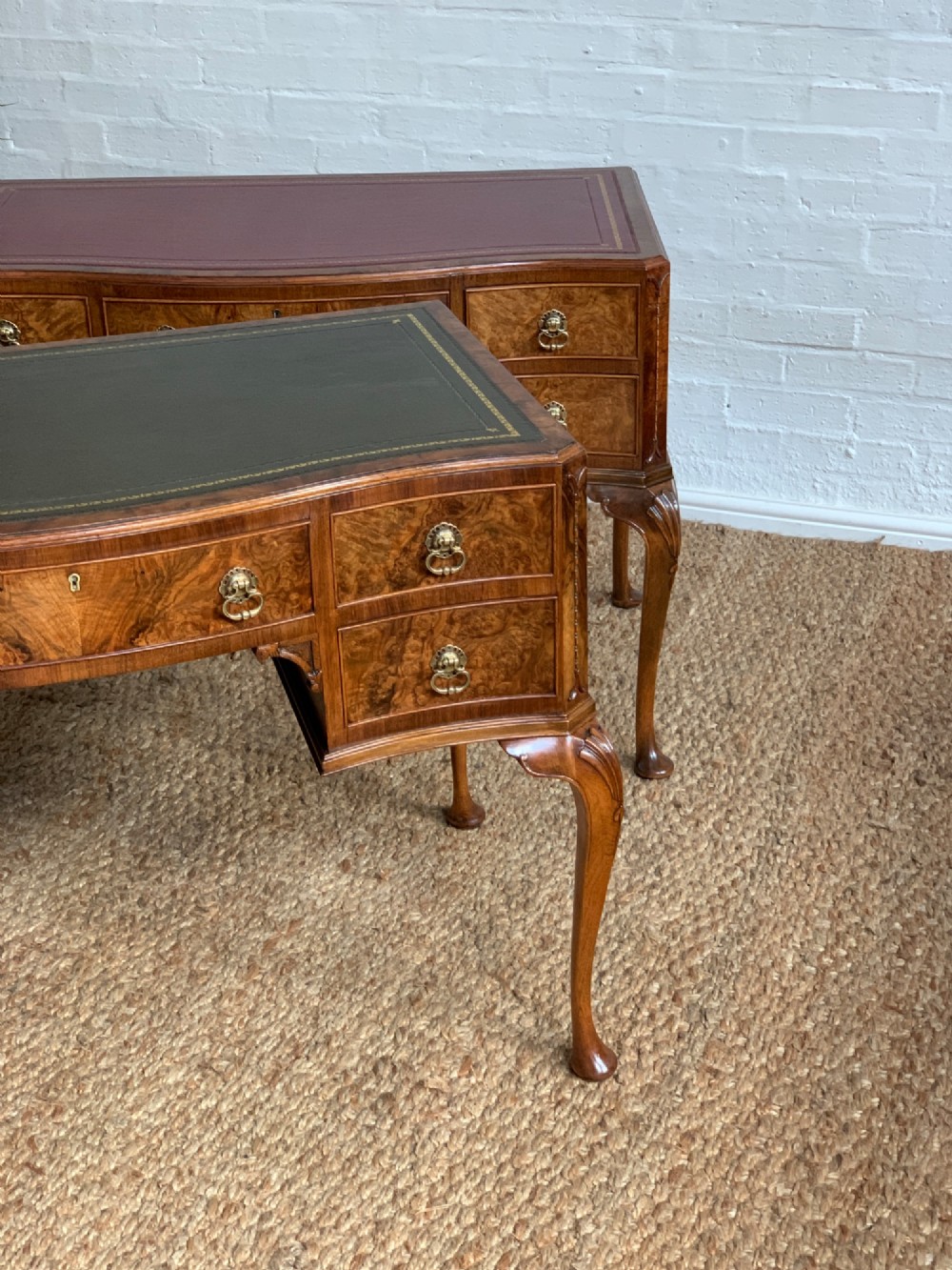 An early 20th-century burr walnut writing desk featuring an inset leather top, kneehole drawer arrangement, brass drop handles, and cabriole legs. View VII