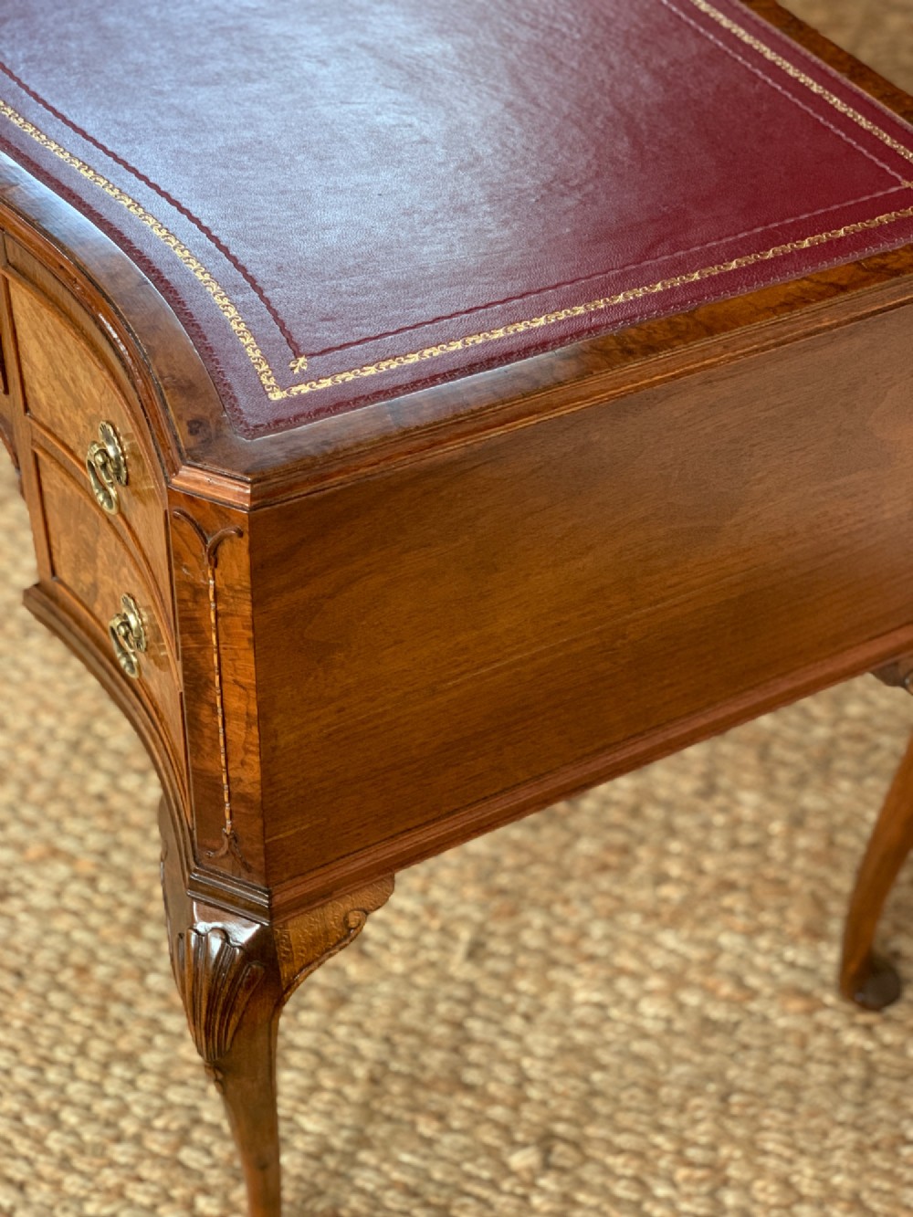 An early 20th-century burr walnut writing desk featuring five drawers with brass handles, carved cabriole legs, and a fitted kneehole. View VI