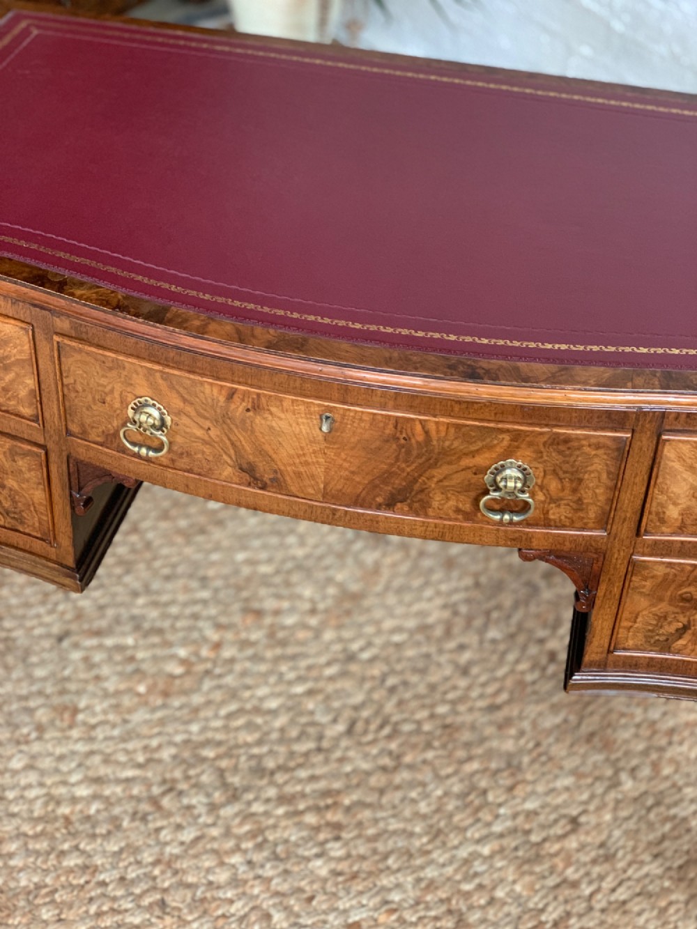 An early 20th-century burr walnut writing desk featuring five drawers with brass handles, carved cabriole legs, and a fitted kneehole. View VII