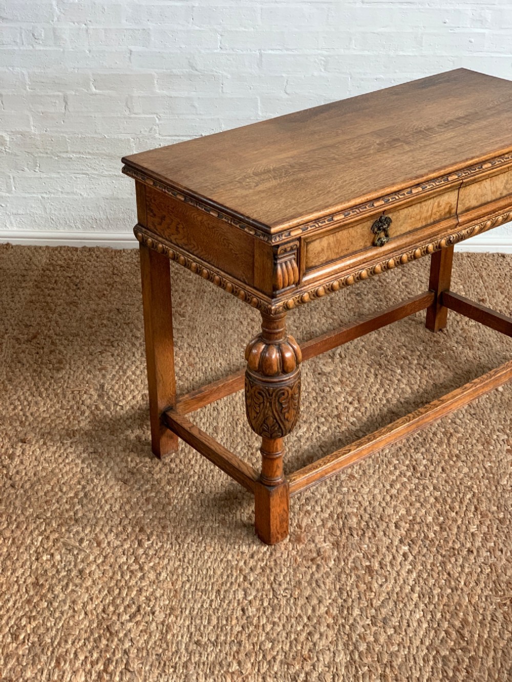 A 1920s carved oak side serving table with two drawers, brass handles, carved bulbous front legs, and a lower stretcher frame. View II