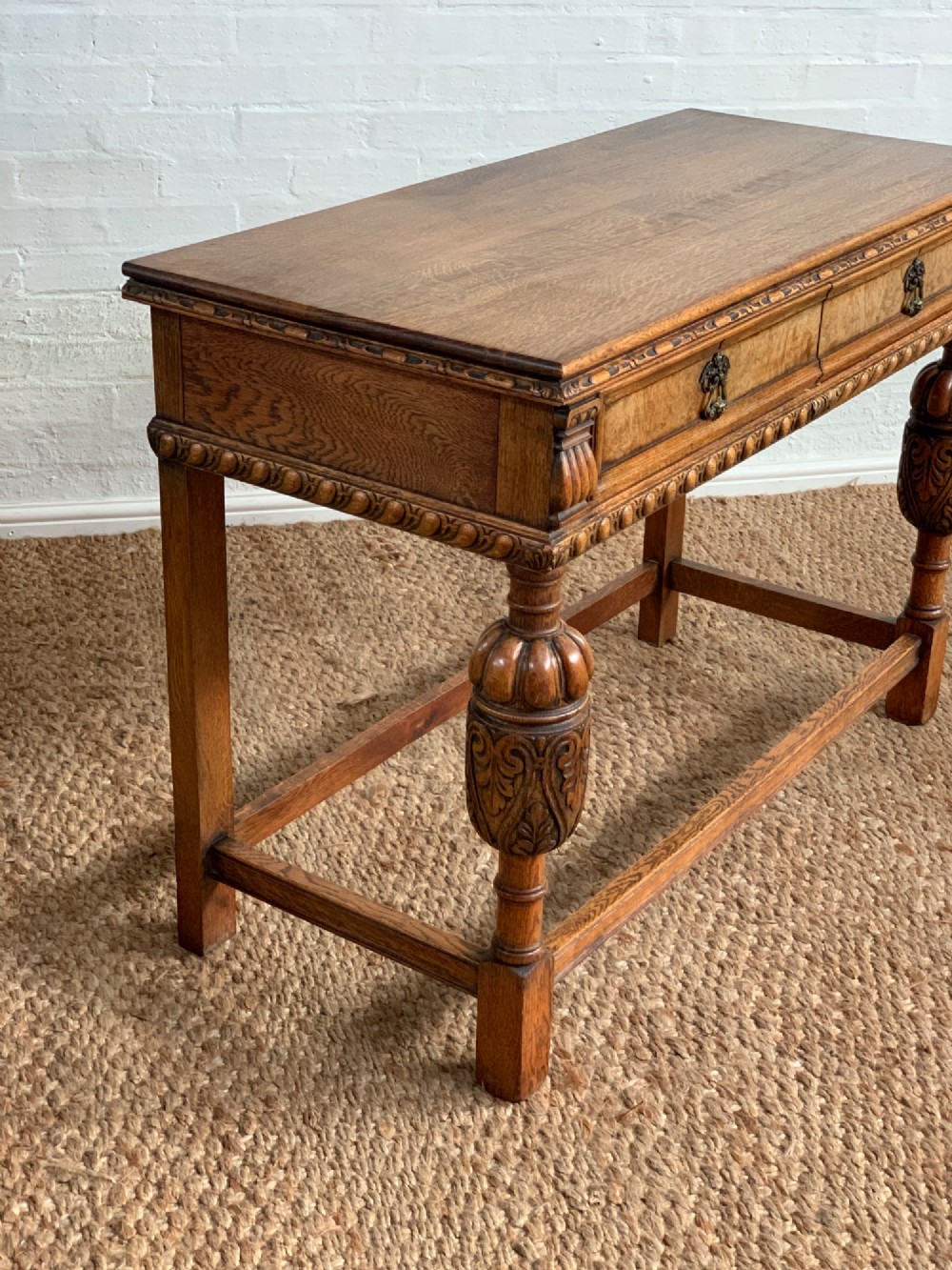 A 1920s carved oak side serving table with two drawers, brass handles, carved bulbous front legs, and a lower stretcher frame. View IV