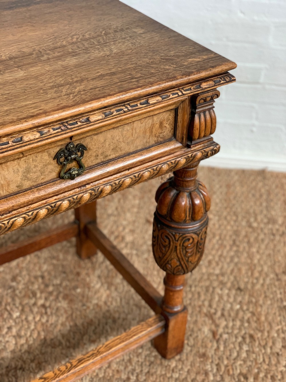 A 1920s carved oak side serving table with two drawers, brass handles, carved bulbous front legs, and a lower stretcher frame. View VI