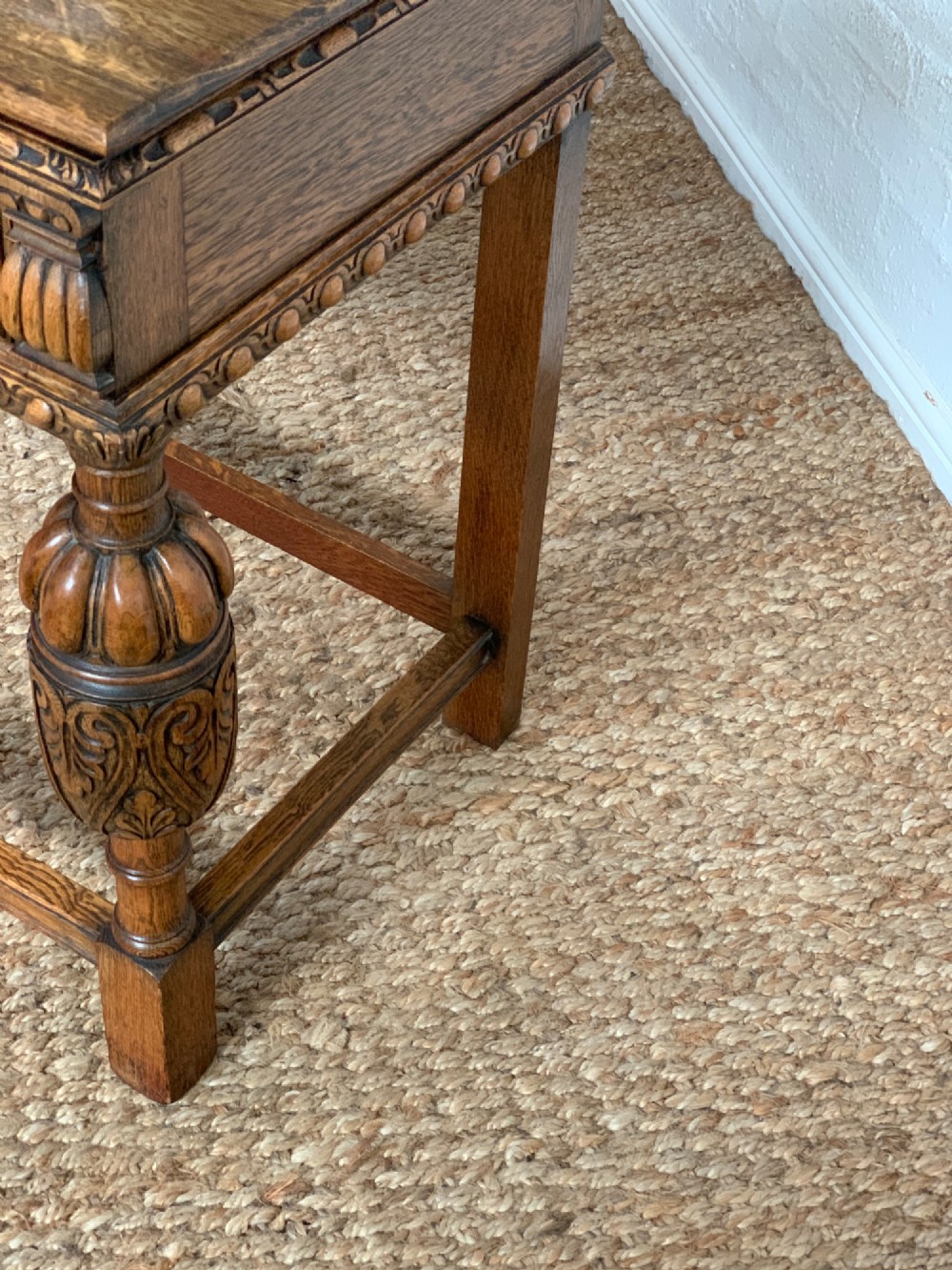 A 1920s carved oak side serving table with two drawers, brass handles, carved bulbous front legs, and a lower stretcher frame. View VII