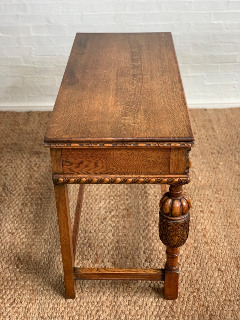 A 1920s carved oak side serving table with two drawers, brass handles, carved bulbous front legs, and a lower stretcher frame. View VIII