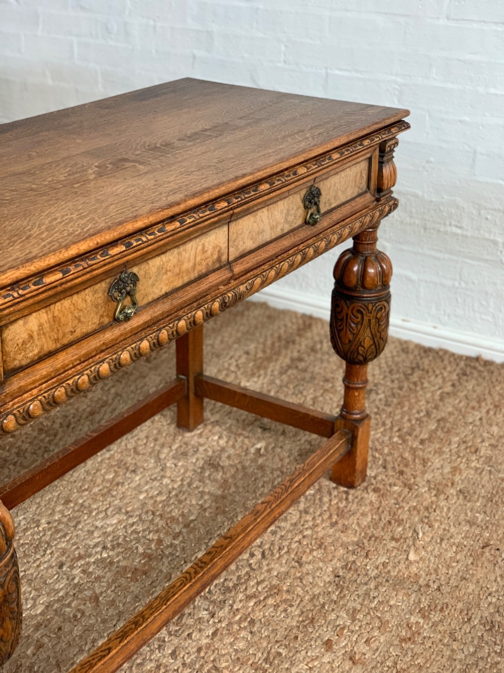 A 1920s carved oak side serving table with two drawers, brass handles, carved bulbous front legs, and a lower stretcher frame. View X
