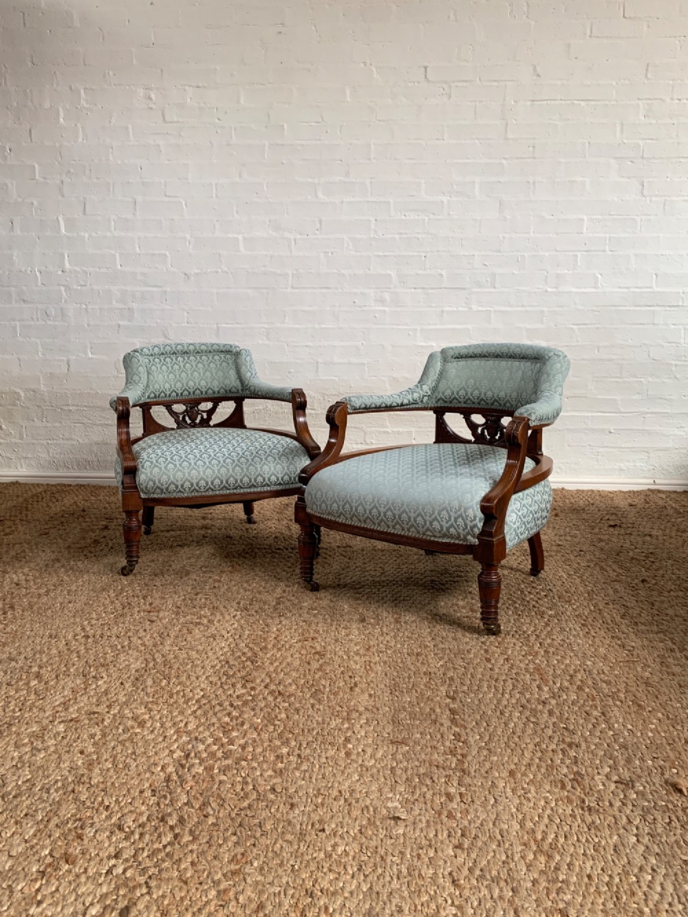 A pair of Edwardian walnut tub armchairs with pale blue patterned upholstery, turned front legs, and castors. View II