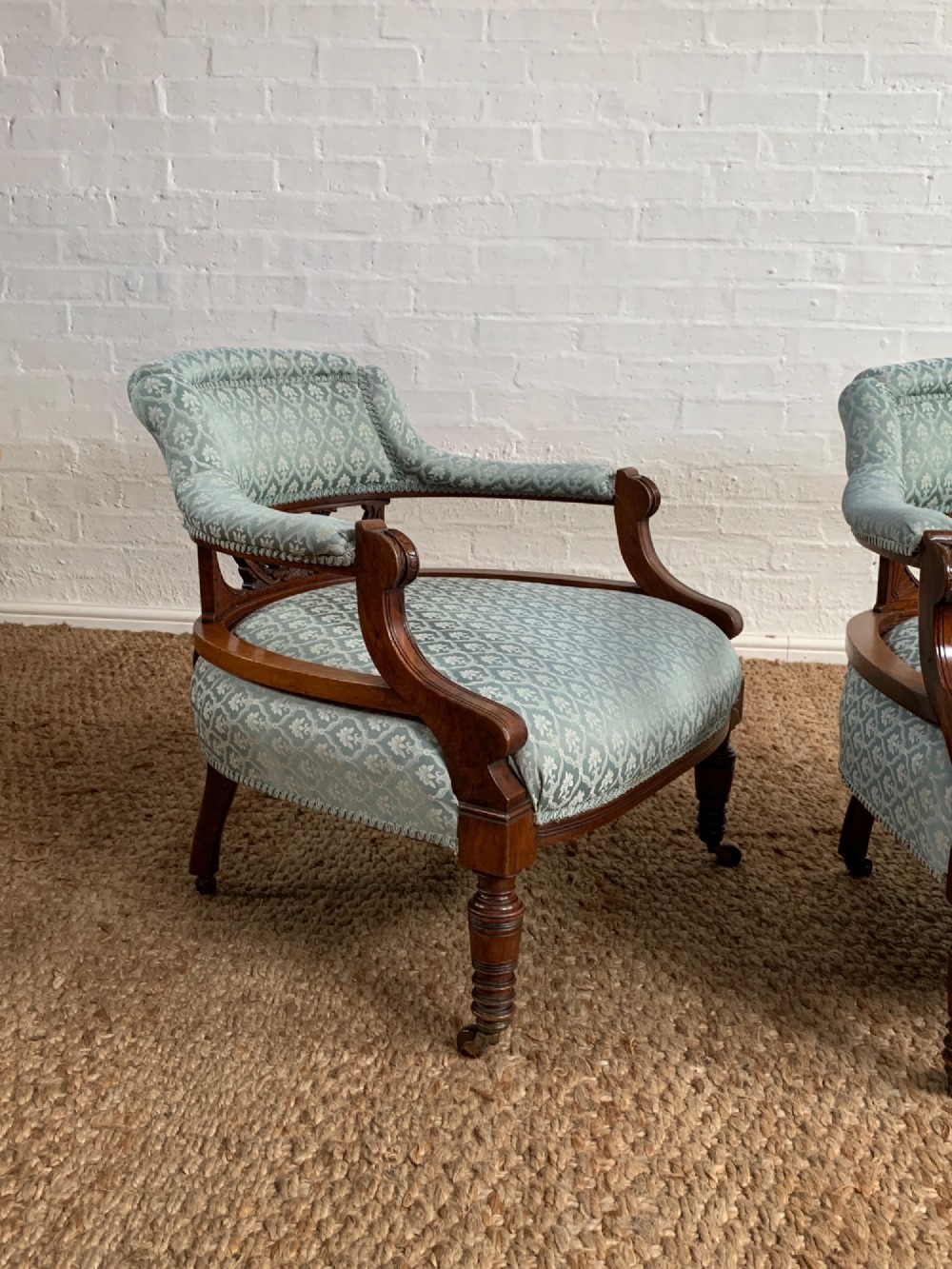 A pair of Edwardian walnut tub armchairs with pale blue patterned upholstery, turned front legs, and castors. View V