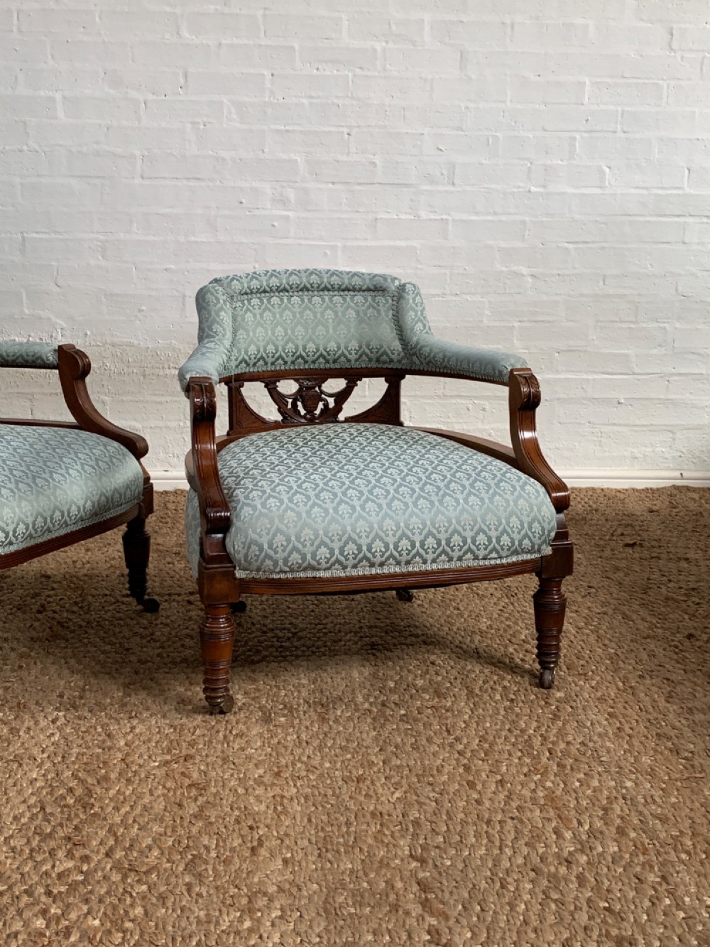 A pair of Edwardian walnut tub armchairs with pale blue patterned upholstery, turned front legs, and castors. View VI