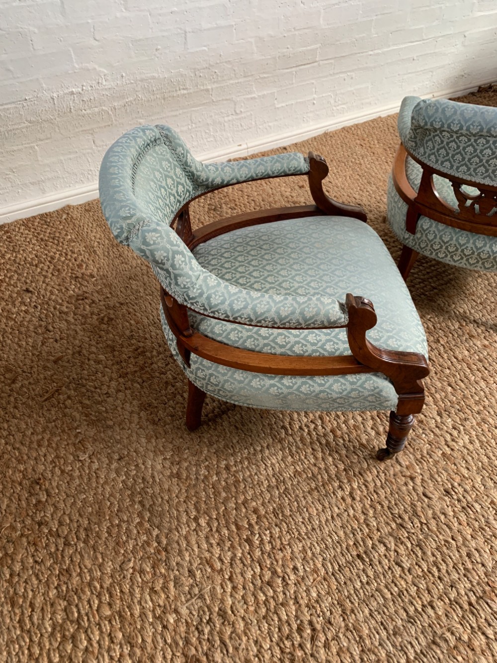A pair of Edwardian walnut tub armchairs with pale blue patterned upholstery, turned front legs, and castors. View IX