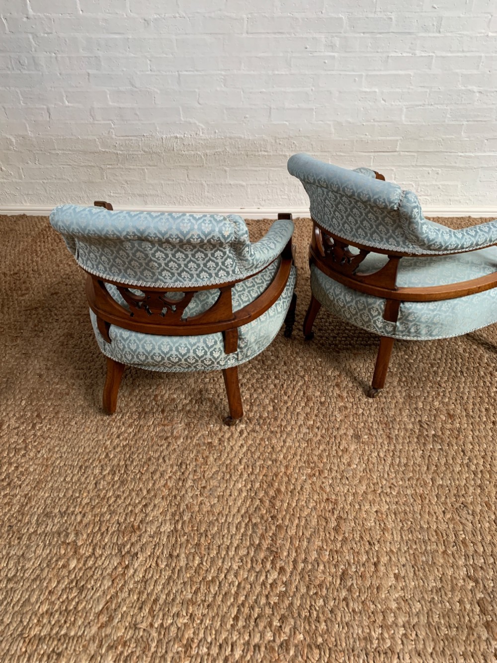 A pair of Edwardian walnut tub armchairs with pale blue patterned upholstery, turned front legs, and castors. View X