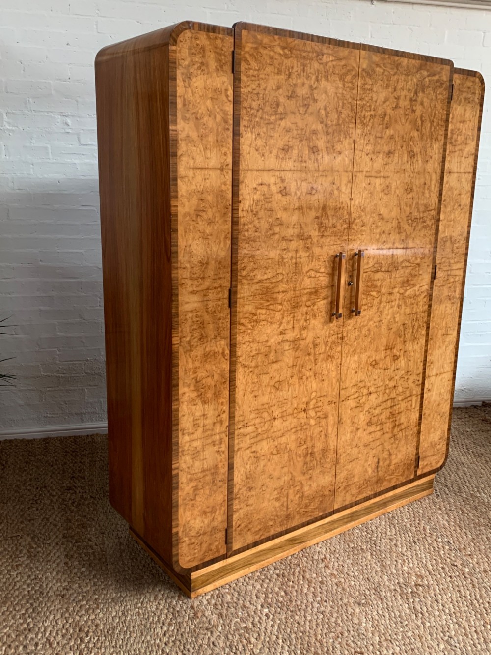 An Art Deco double wardrobe crafted from figured burr walnut veneer with rounded top edges, vertical wooden handles, and a stepped plinth base. View II