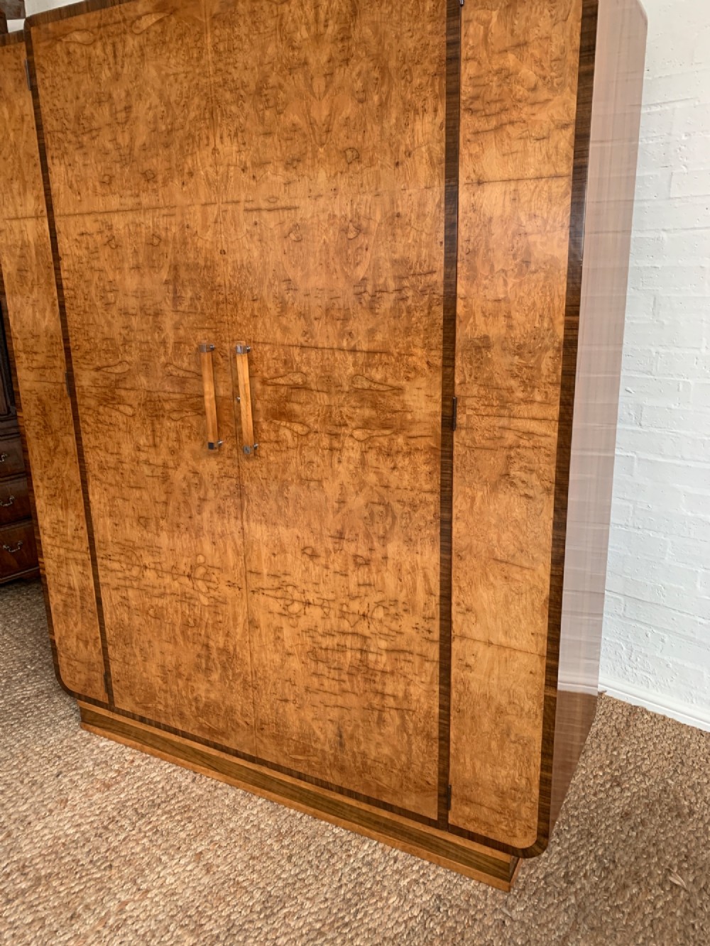 An Art Deco double wardrobe crafted from figured burr walnut veneer with rounded top edges, vertical wooden handles, and a stepped plinth base. View III