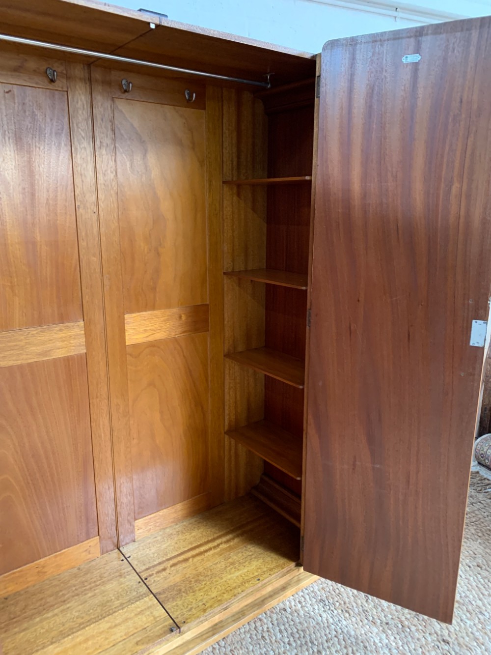 An Art Deco double wardrobe crafted from figured burr walnut veneer with rounded top edges, vertical wooden handles, and a stepped plinth base. View V