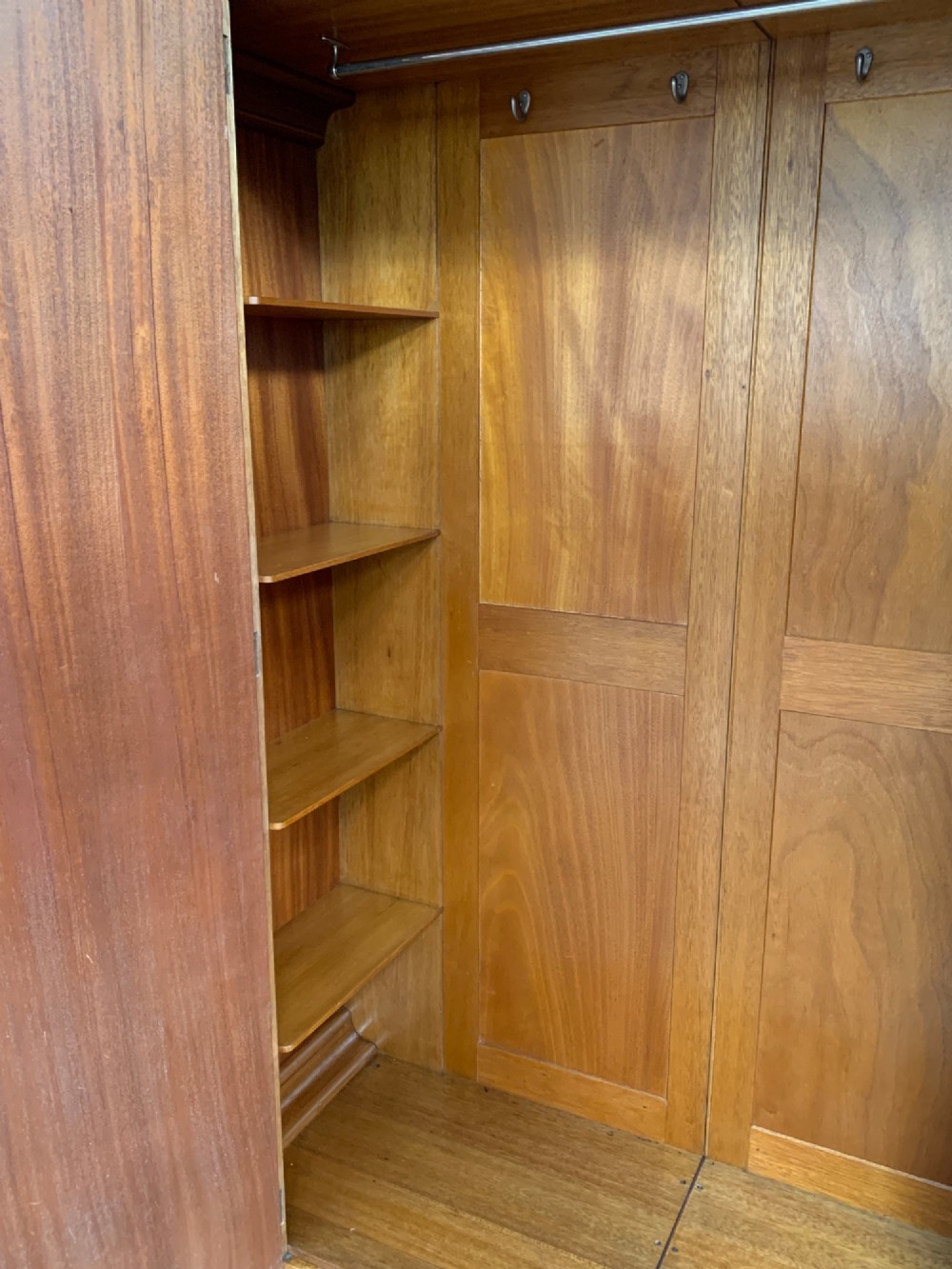 An Art Deco double wardrobe crafted from figured burr walnut veneer with rounded top edges, vertical wooden handles, and a stepped plinth base. View VI