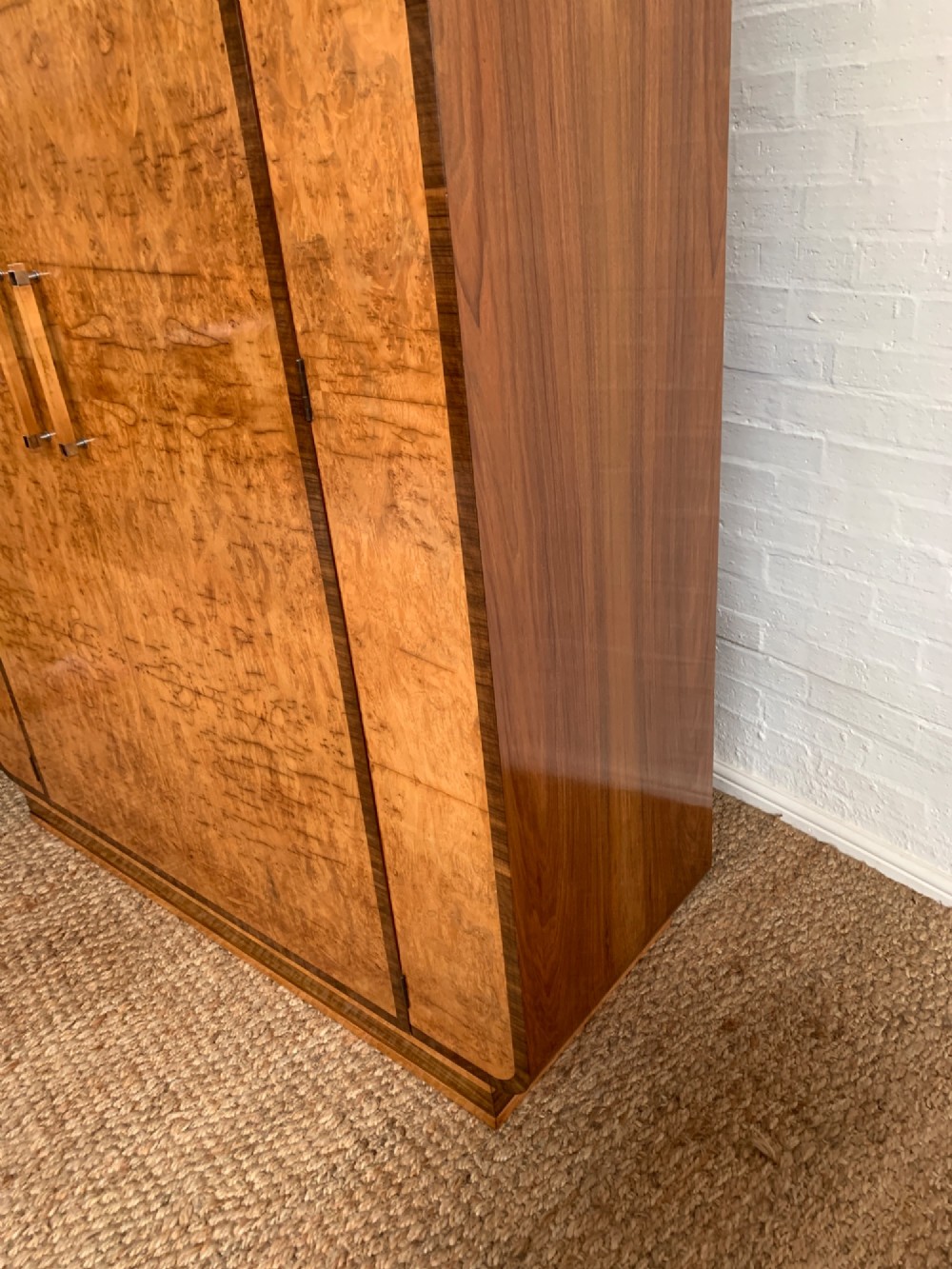 An Art Deco double wardrobe crafted from figured burr walnut veneer with rounded top edges, vertical wooden handles, and a stepped plinth base. View VIII
